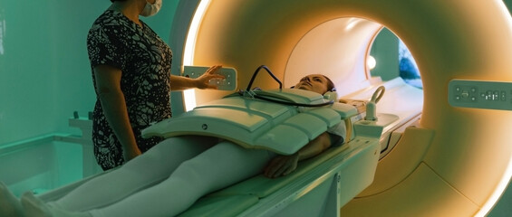 Doctor or nurse and patient with tomography CT or MRI Scan in hospital. Interior of radiography...