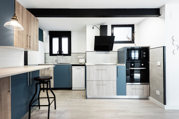 Kitchen with black appliances, combined indigo blue and light wood furniture with black metal beam