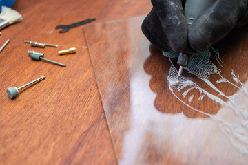 A craftsman does glass engraving with a rotary tool