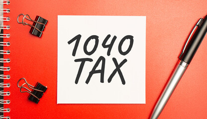 1040 tax sign on sheet of paper on the red notepad with pen