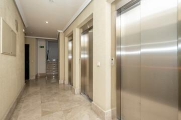 Lobby of a building with three elevators with cream marble floors