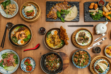 Asian and Japanese food dishes set with assorted ramen, fried duck, bao pan, wok noodles, soy sauce, mushrooms, and appetizers