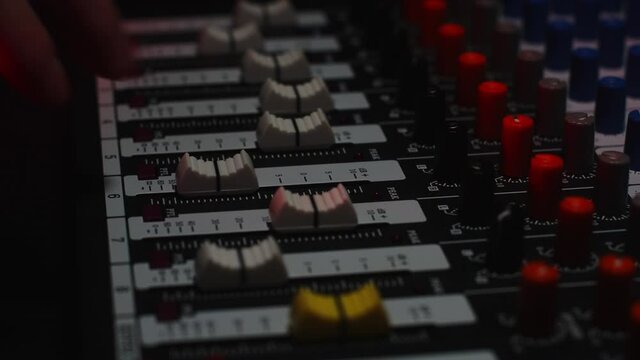 The sound engineer controls the volume sliders using the digital volume control
