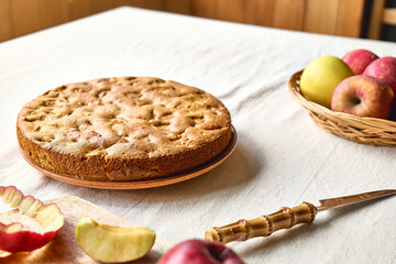 Homemade apple cake Charlotte, american sponge apple pie with walnuts and ripe red apples on the table with linen tablecloth. Healthy seasonal eating.