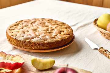 Homemade apple cake Charlotte, american sponge apple pie with walnuts and ripe red apples on the table with linen tablecloth. Healthy seasonal eating.