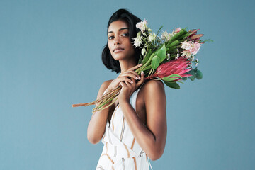 Flatter me with flowers not compliments. Cropped shot of a beautiful young woman posing with a...