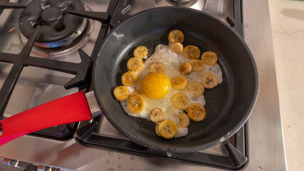 Cooking process of fried bananas with scrambled eggs. Fried Banana with eggs in hot pan.