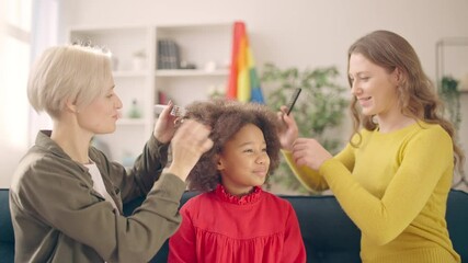 Two young women combing little African American daughter multiracial lgbt family