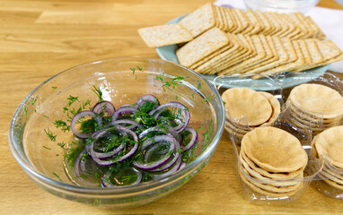 The process of preparing a festive snack on toast with sprats, onions, eggs and tomatoes. close up
