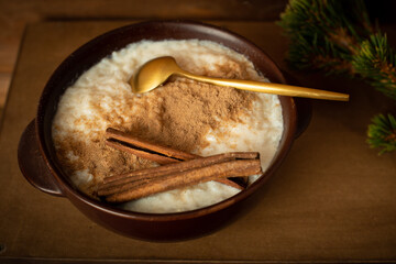 Delicious rice pudding with cinnamon in bowl on wooden background