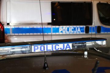 Sygnalizator błyskowy niebieski na dachu radiowozu policji polskiej w nocy na drodze. 