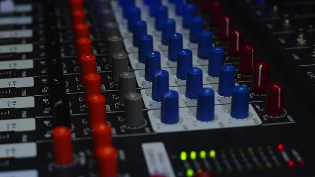 Sound engineer raises the volume of music at a party using a professional mixer