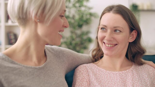 Gay couple expecting baby, happy pregnant woman sitting on couch with girlfriend