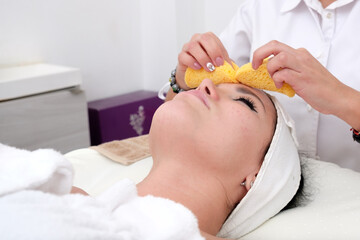 Obraz na płótnie Canvas Facial treatment that allows women to rejuvenate. Dermatologist applies a facial treatment to a young white woman, who is lying in a clinic specializing in skin rejuvenation.