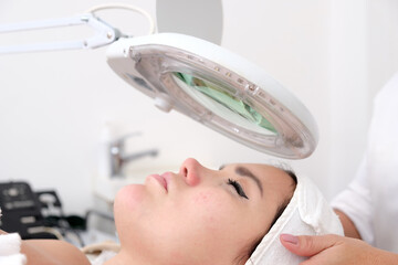 Facial treatment that allows women to rejuvenate. Dermatologist applies a facial treatment to a young white woman, who is lying in a clinic specializing in skin rejuvenation.