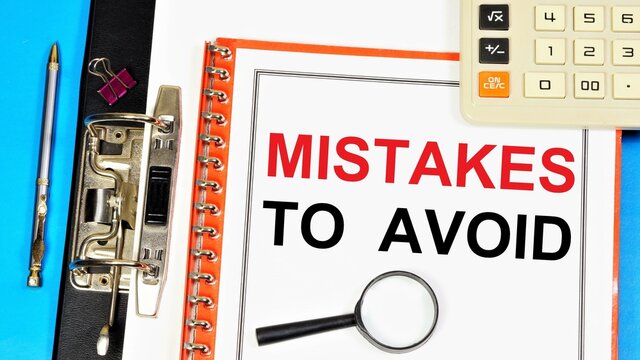 Mistakes to avoid. The inscription in the planning folder, on the background of a calculator, magnifying glass and a pen for writing.