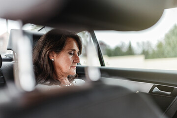 close-up view of mature hispanic woman face on a taxi backseat looking her phone