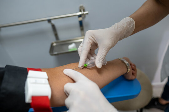 Blood test at a laboratory, nurse taking blood sample from a woman's arm using a syringe