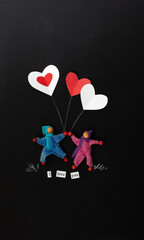 2 gender neutral characters holding heart balloons on a chalkboard background vertical, portrait orientation, black background, copy space