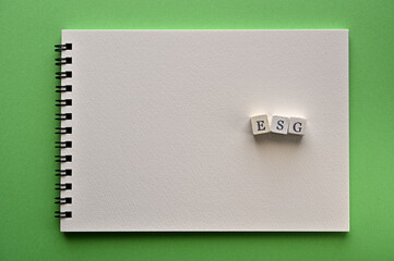 On a white sketchbook, white cubes are arranged in the letters "ESG". It is an acronym for Environmental, Social and Governance. Copy space is available.