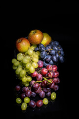 Apples, green and red grapes on a black background, still life