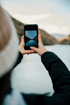 girl taking a photo of a beautiful landscape with her smartphone