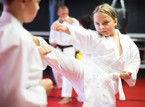 Preteen children practicing new karate moves in pairs at sport gym
