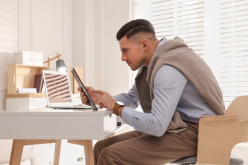 Man with poor posture using tablet at table indoors
