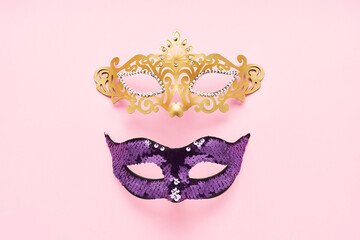 Fototapeta premium Two colorful carnival masks on a light pink background. Carnival celebration concept. Top view