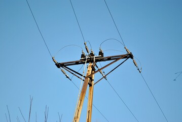 The power pole against the blue sky. Beautiful weather. 
