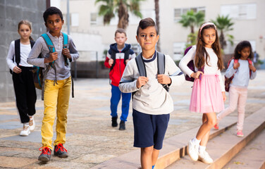 Obraz premium Portrait of preteen Hispanic boy with rucksack walking outdoors on his way to school on warm autumn day. Back to school concept.