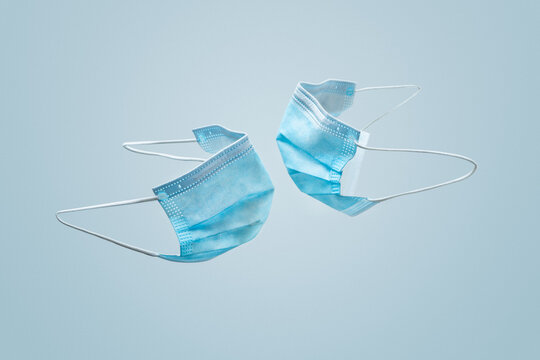 Dos mascarillas m&eacute;dicas protectoras suspendidas en el aire, una frente a otra, cerca, simulando darse un beso, par de m&aacute;scaras quir&uacute;rgicas a punto de besarse