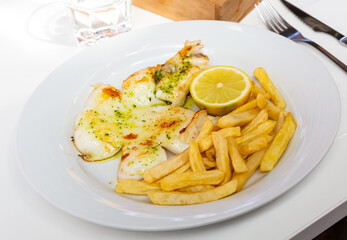 Delicious seafood dish - roasted in oil cuttlefish served with French fries and lemon
