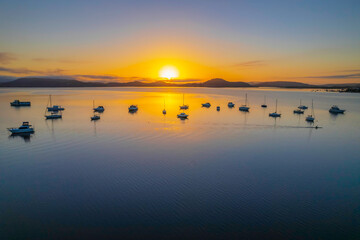 Sunrise waterscape with boats, soft clouds and reflections