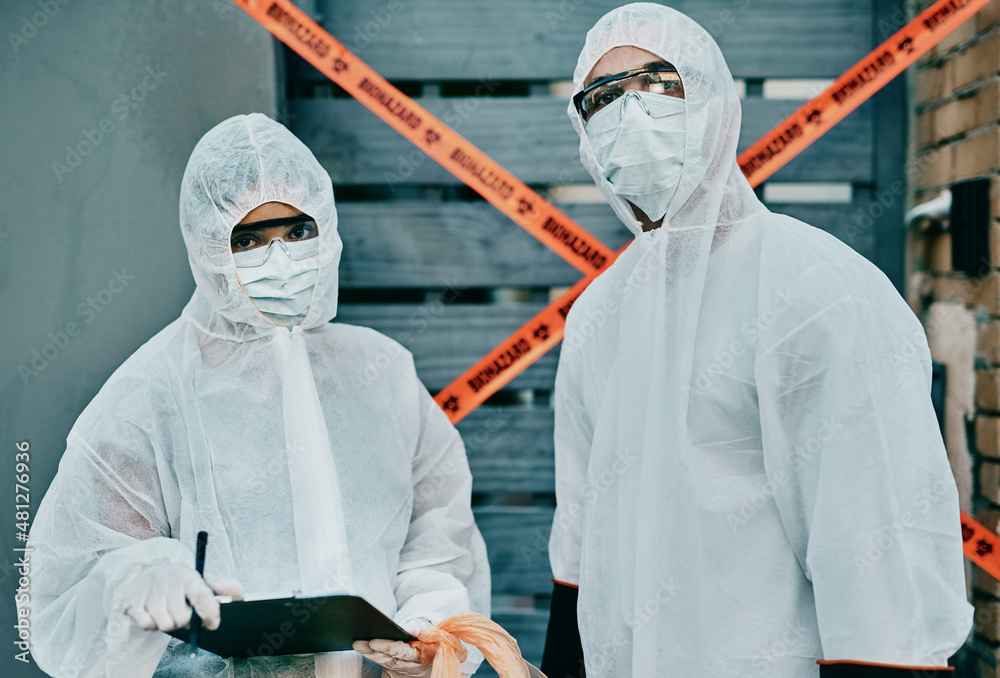 Poster working together to save the world. shot of two healthcare workers wearing hazmat suits working toge