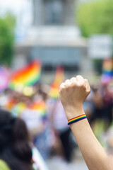 a person raising his fist with a rainbow bracelet in a gay pride parade in the streets of Mexico City