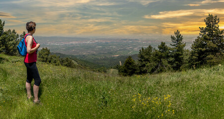 Obraz premium Girl with blue backpack and sport clothes, enjoying from the mountain valley in magical moments.
