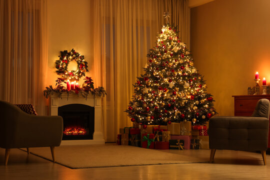 Beautiful Christmas tree and gifts near fireplace in festively decorated living room