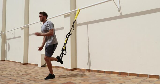 Fitness suspension straps man training legs with suspended lunge exercise at gym. Lower body workout.