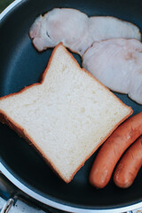 Frying pan with tasty sausages, ham and toast. Homemade delicious American breakfast. Nutritious, tasty, healthy food.