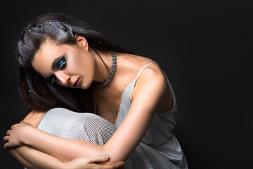 Naklejka premium Beautiful woman with makeup in creative image of winter, snow queen or other sad character isolated on black background.
