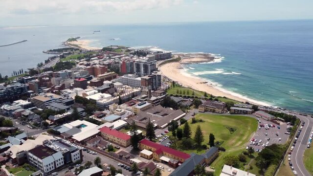 Aerial drone view of the city CBD buildings with Newcastle Beach Nobbys harbour and break wall Tourism Pacific Ocean NSW Australia 4K