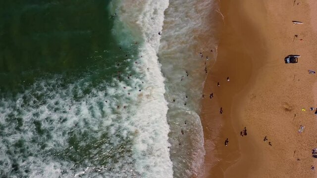 Aerial drone Bird's-eye shot of people swimming in sandy Newcastle Beach lifeguards waves and tourism NSW Australia 4K