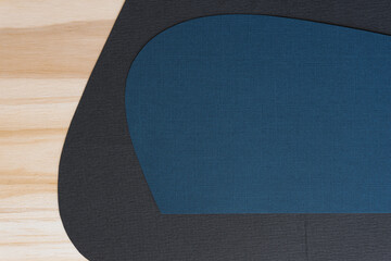 curvy blue paper in dialogue with a black shape on a wooden space