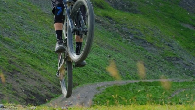 A mountain biker does a jump in slow motion and compresses the suspension