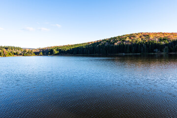 Fototapeta na wymiar Spruce Knob Lake blue water in West Virginia Appalachian mountains sunset in Monongahela National Forest late autumn fall season foliage reflection