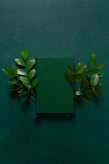 Book on deep green background. Flat lay, top view. Aesthetic all green composition.