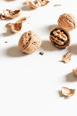 Cosy autumn aesthetic composition with dry  leaves, walnuts on white background. Flat lay, top view, copy space.