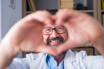 Man doing heart shape gesture with hands. Smiling handsome caucasian male doctor making a love...