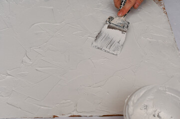 applying a layer of putty on a sheet of fiberboard with a spatula. the process of making a...
